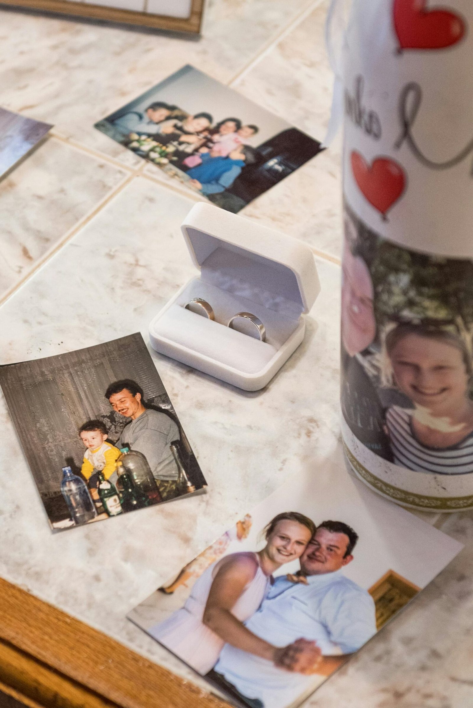 A nostalgic display of wedding rings and family photographs on a marble surface.